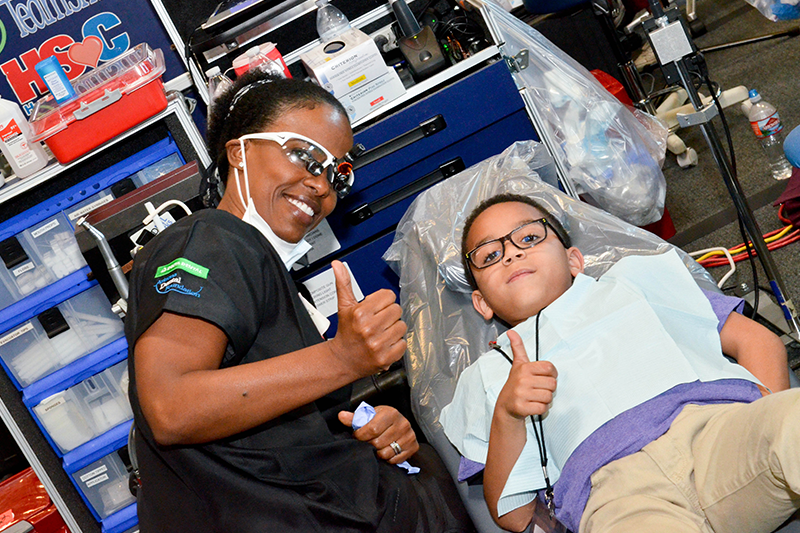 oral health professional and young boy during an oral health screening giving a thumbs up at a volunteer event 