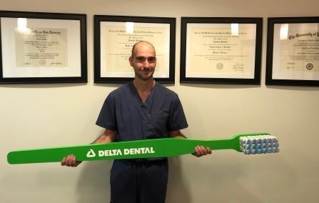 in-network dentist holding life size Delta Dental toothbrush 