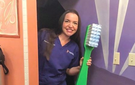 in-network dentist holding life size Delta Dental toothbrush 