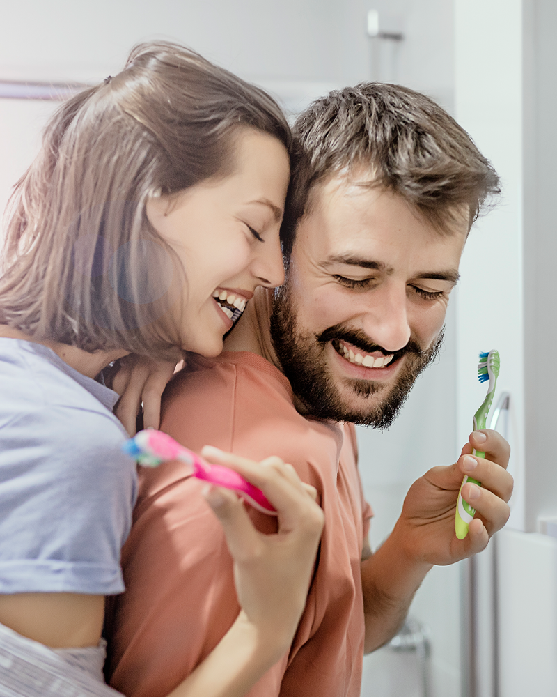 Smiling couple improving their oral health by brushing their teeth in the bathroom together 